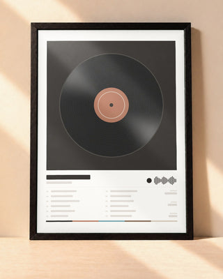 Poster album personnalisé dans un cadre noir, posé contre un mur clair