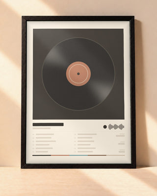Poster album personnalisé dans un cadre noir, posé contre un mur clair