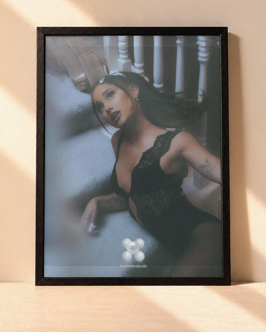 Poster Ariana Grande – Positions encadré dans un cadre noir, posé contre un mur clair