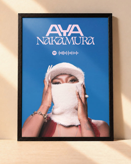 Poster Aya Nakamura – DNK encadré dans un cadre noir, posé contre un mur clair