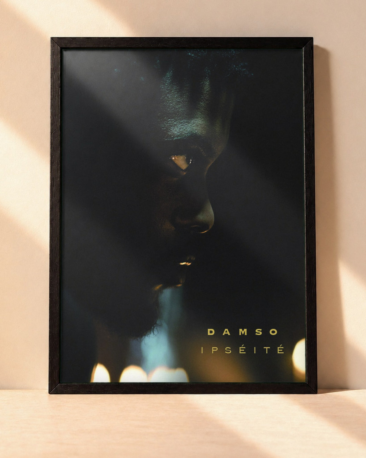 Poster Damso – Ipséité encadré dans un cadre noir, posé contre un mur clair