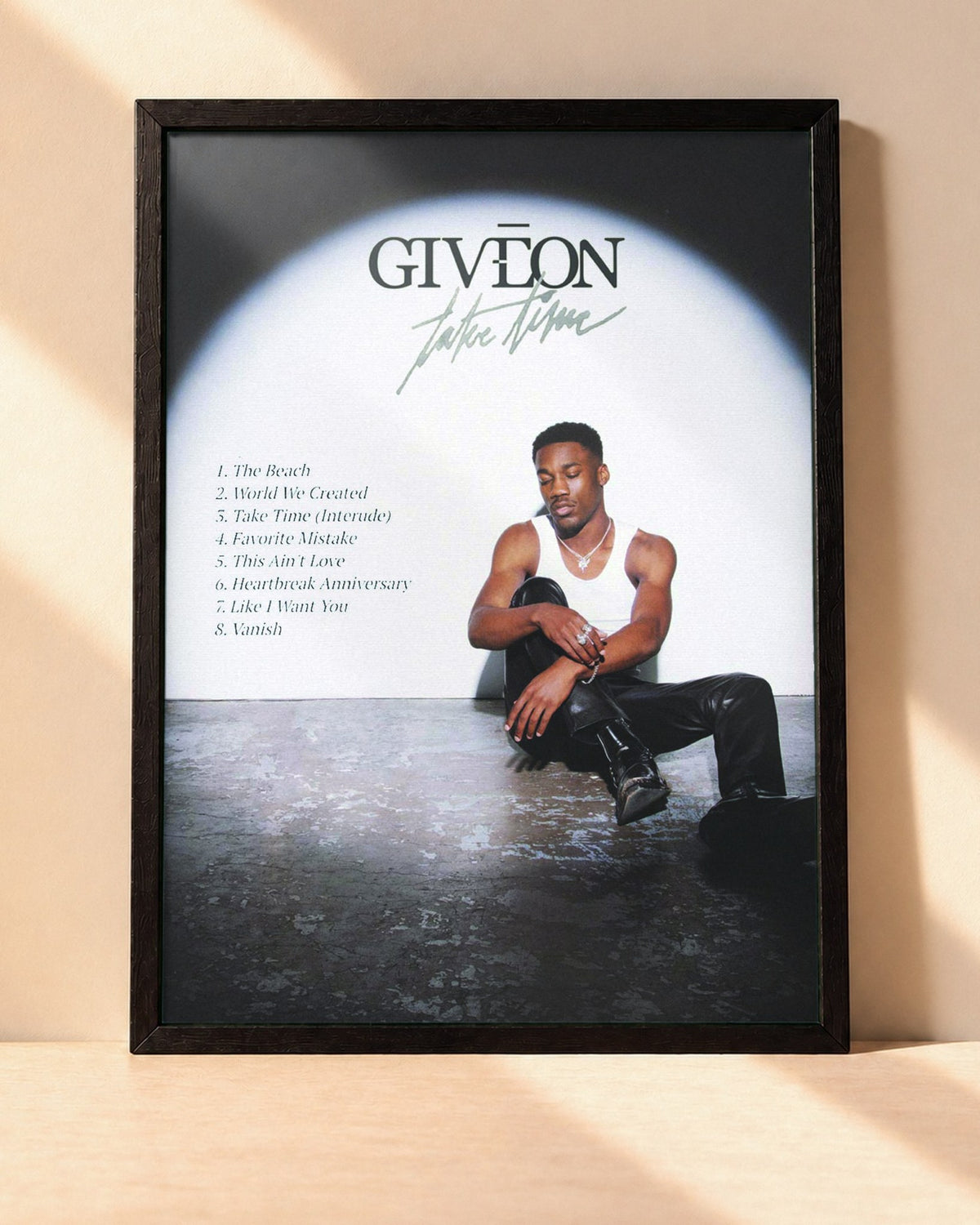 Poster Giveon – Take Time encadré dans un cadre noir, posé contre un mur clair