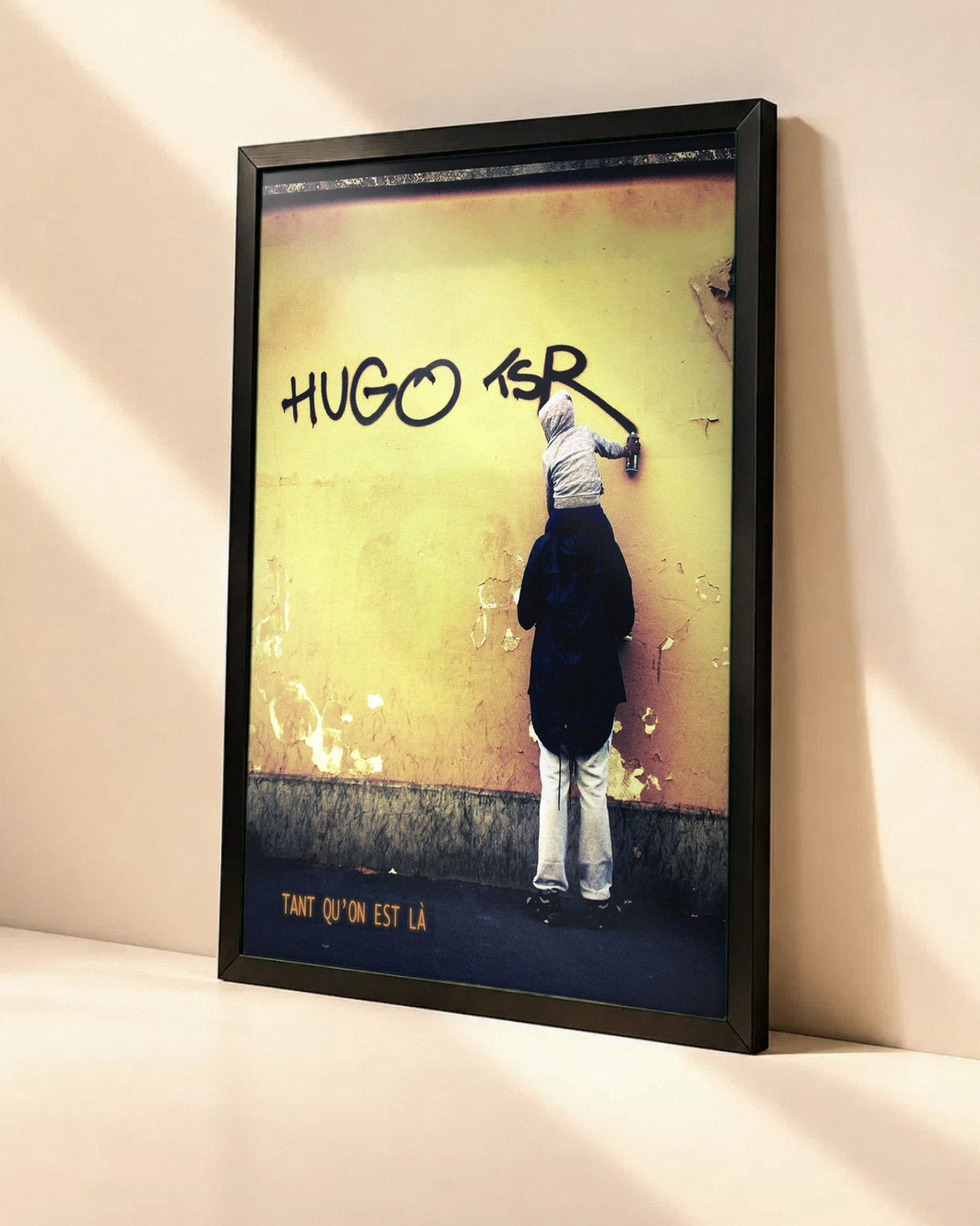 Poster Hugo TSR – Tant Qu'on Est Là dans un cadre noir, vue en angle