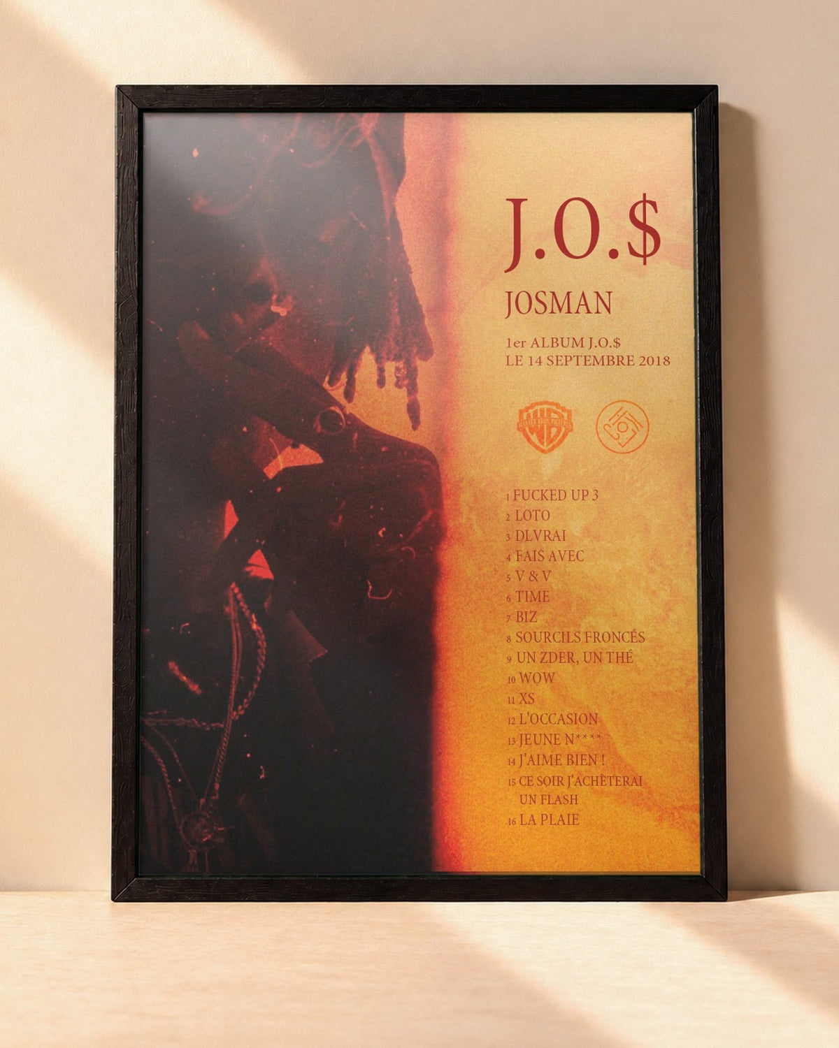 Poster Josman – JO$ encadré dans un cadre noir, posé contre un mur clair