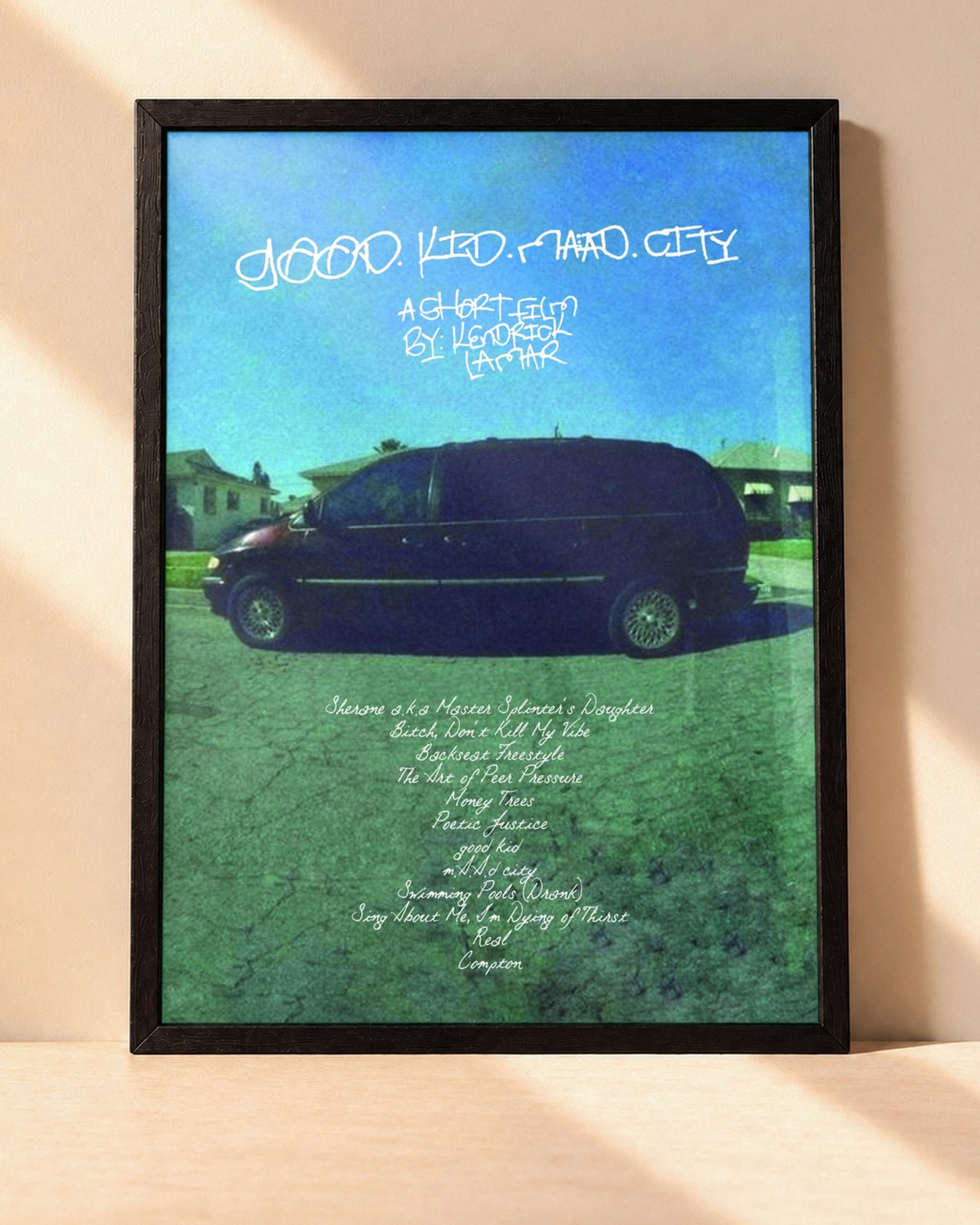 Poster Kendrick Lamar – Good Kid, M.A.A.D City encadré dans un cadre noir, posé contre un mur clair