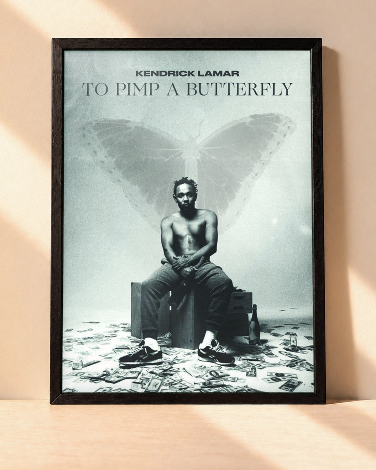 Poster Kendrick Lamar – To Pimp A Butterfly encadré dans un cadre noir, posé contre un mur clair