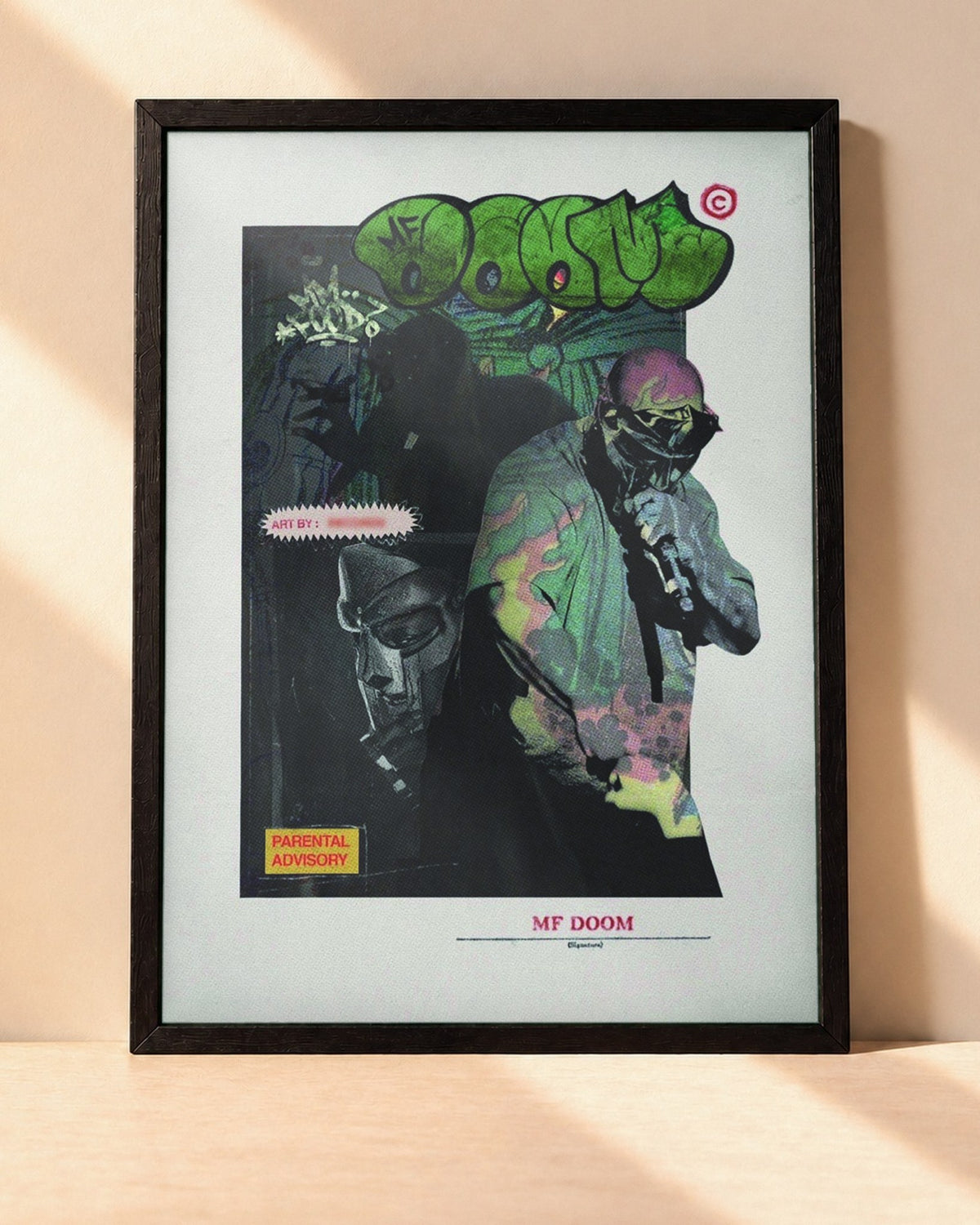 Poster MF DOOM encadré dans un cadre noir, posé contre un mur clair