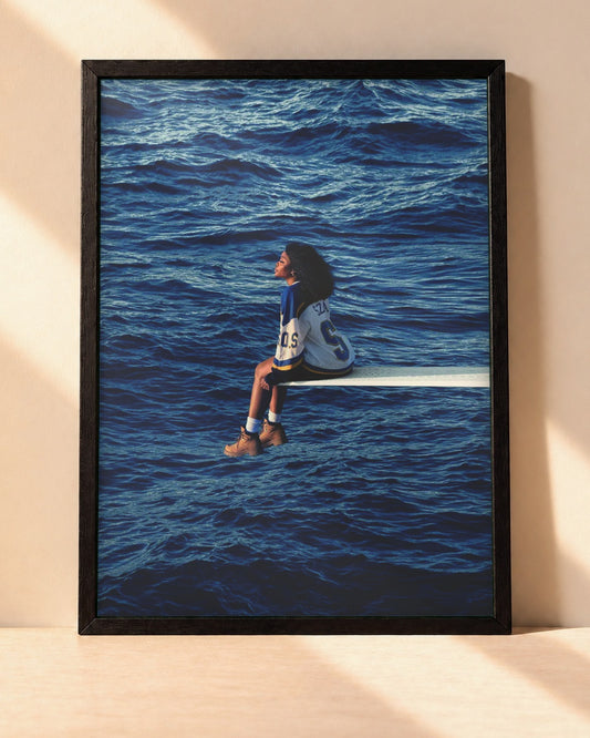 Poster SZA – SOS encadré dans un cadre noir, posé contre un mur clair