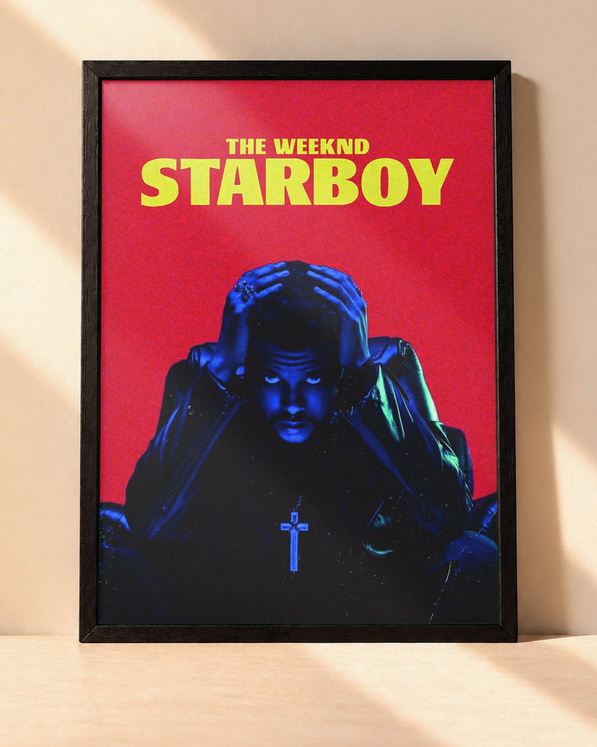 Poster The Weeknd – Starboy encadré dans un cadre noir, posé contre un mur clair