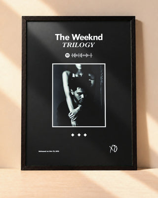 Poster The Weeknd – Trilogy encadré dans un cadre noir, posé contre un mur clair