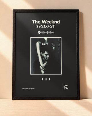 Poster The Weeknd – Trilogy encadré dans un cadre noir, posé contre un mur clair