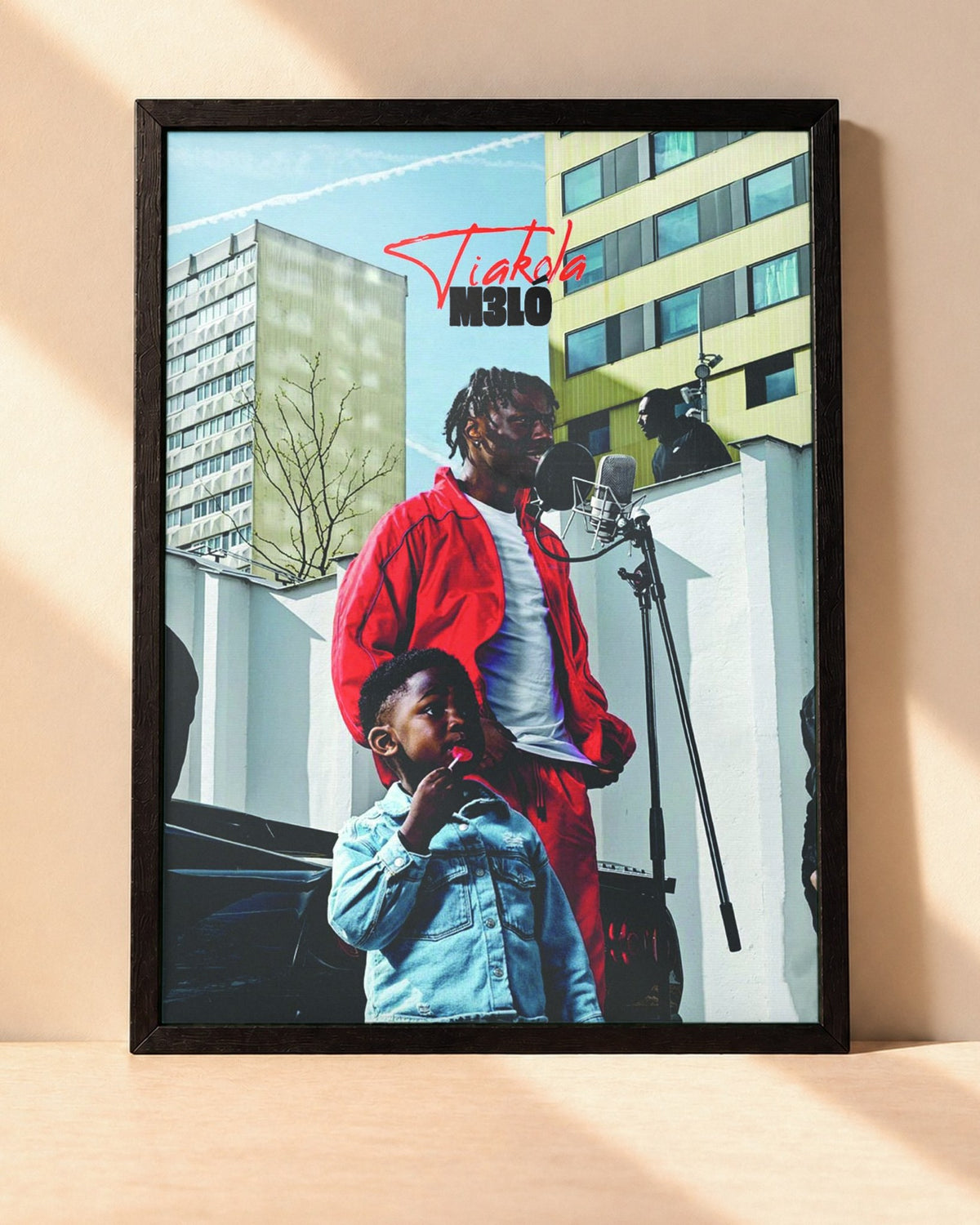 Poster Tiakola – Mélo encadré dans un cadre noir, posé contre un mur clair